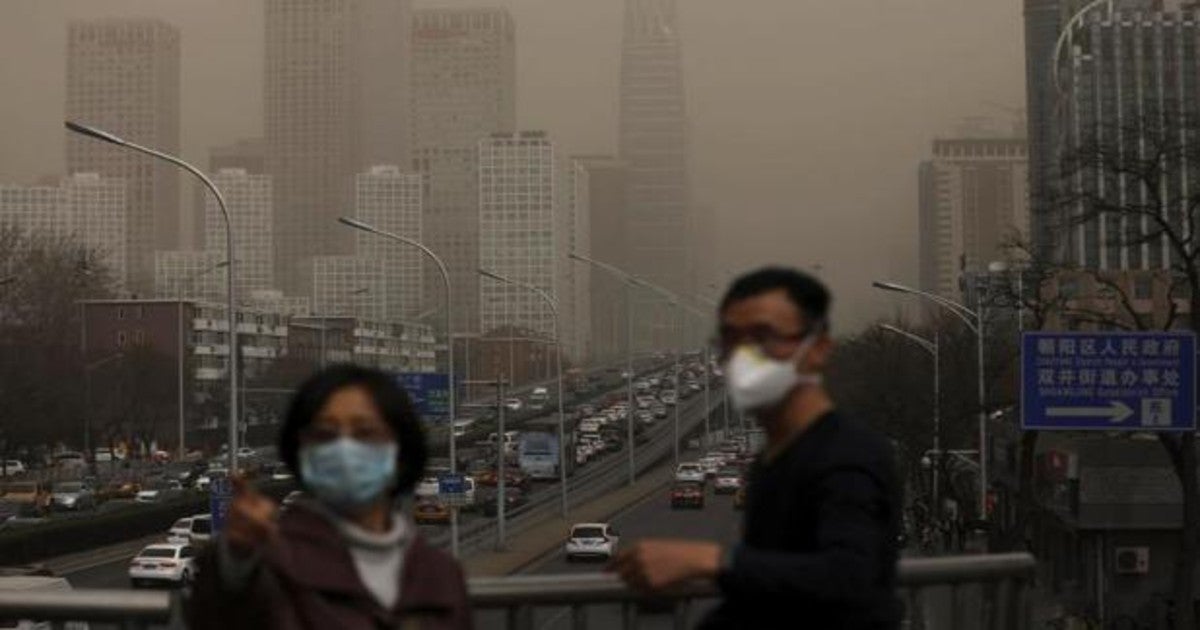 Imagen de archivo en la que seve a un hombre y una mujer que se protegen con máscaras de la nube de contaminación que cubre la ciudad de Pekín (China)