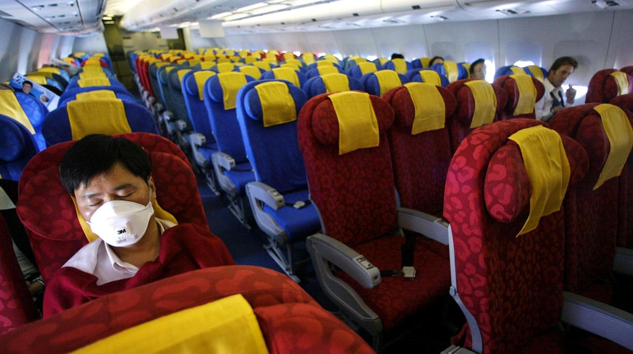 Un pasajero de un vuelo de Hong Kong se protege con una máscara durante la epidemia del SARS