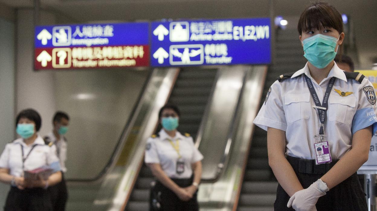 Un grupo de sanitarios del Departamento de Sanidad de Hong Kong se prepara para tomar la temperatura a los pasajeros que llegan al aeropuerto