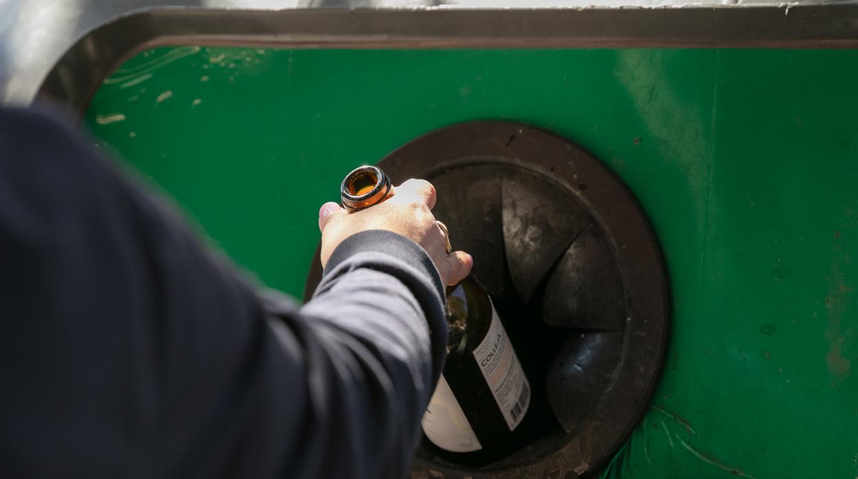 Un hombre recicla una botella de vino