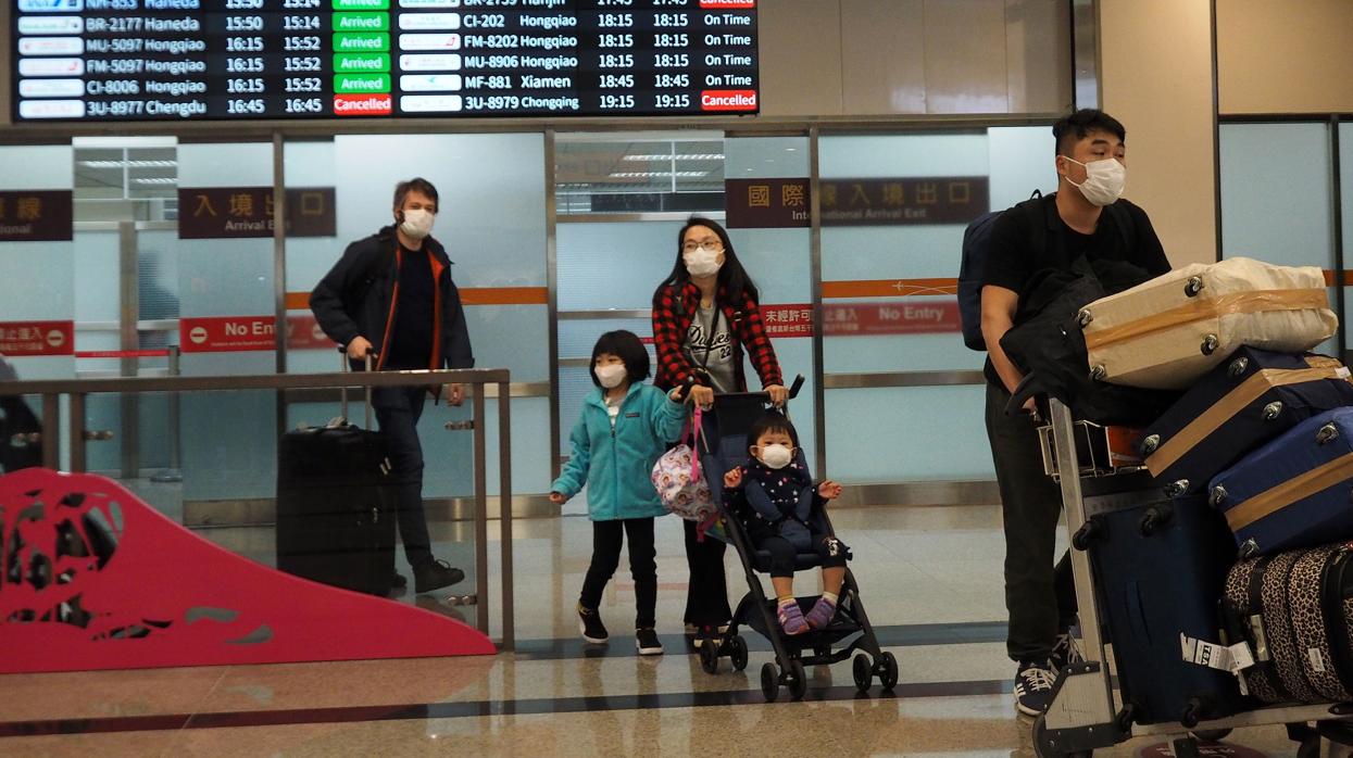 Pasajeros llegan con mascarillas al aeropuerto de Taipéi Songshan