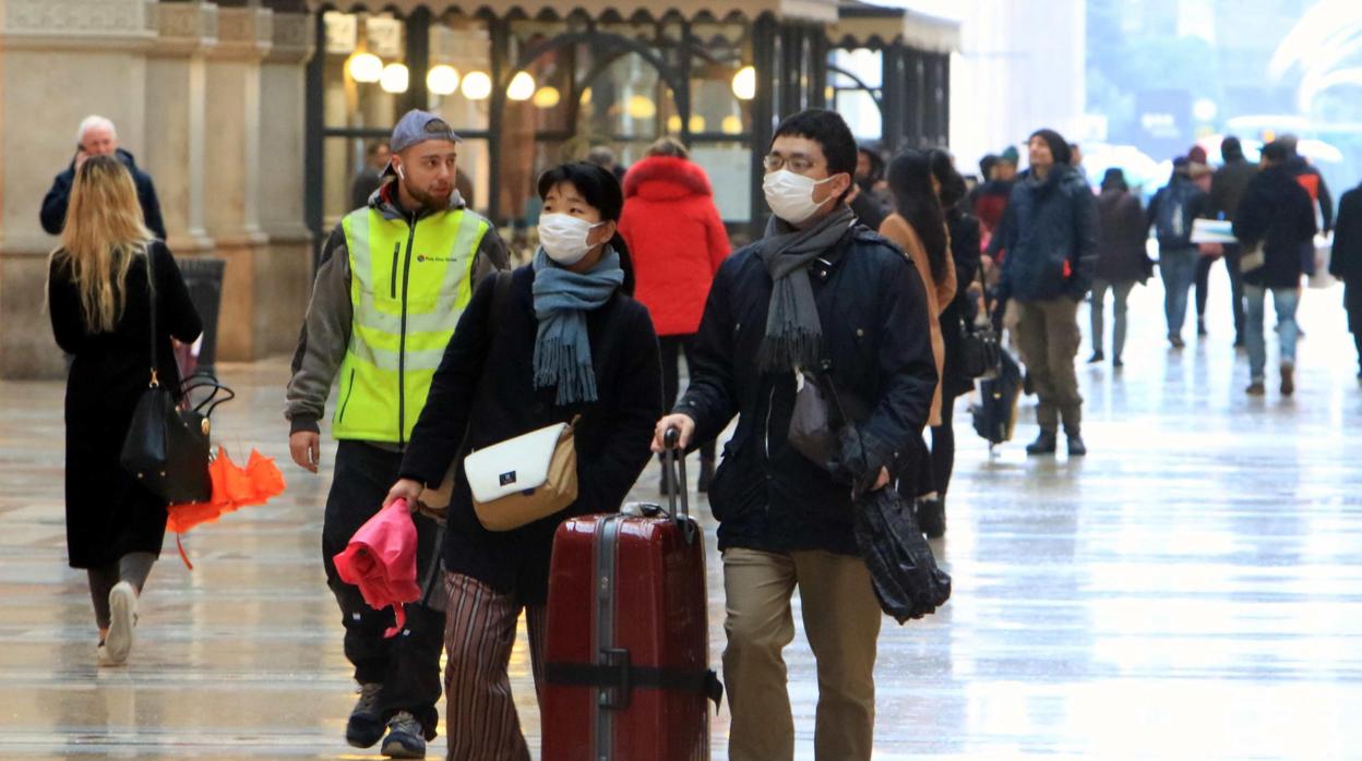 Dos turistas asiáticos llevan una máscara protectora al aterrizar en el centro de Milán, en la galería Vittorio Emanuele