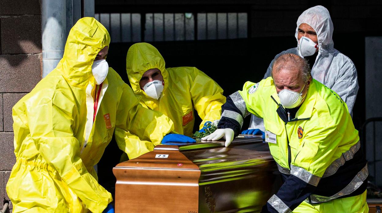 Agentes cargan el ataúd de una persona fallecida a causa del coronavirus en Italia