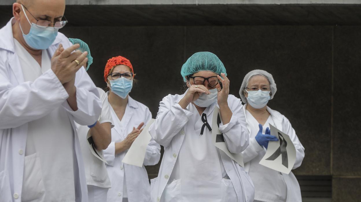 Sanitarios aplauden conmocionados tras el minuto de silencio en la entrada del Hospital Doctor Peset por la técnica de enfermería fallecida por coronavirus