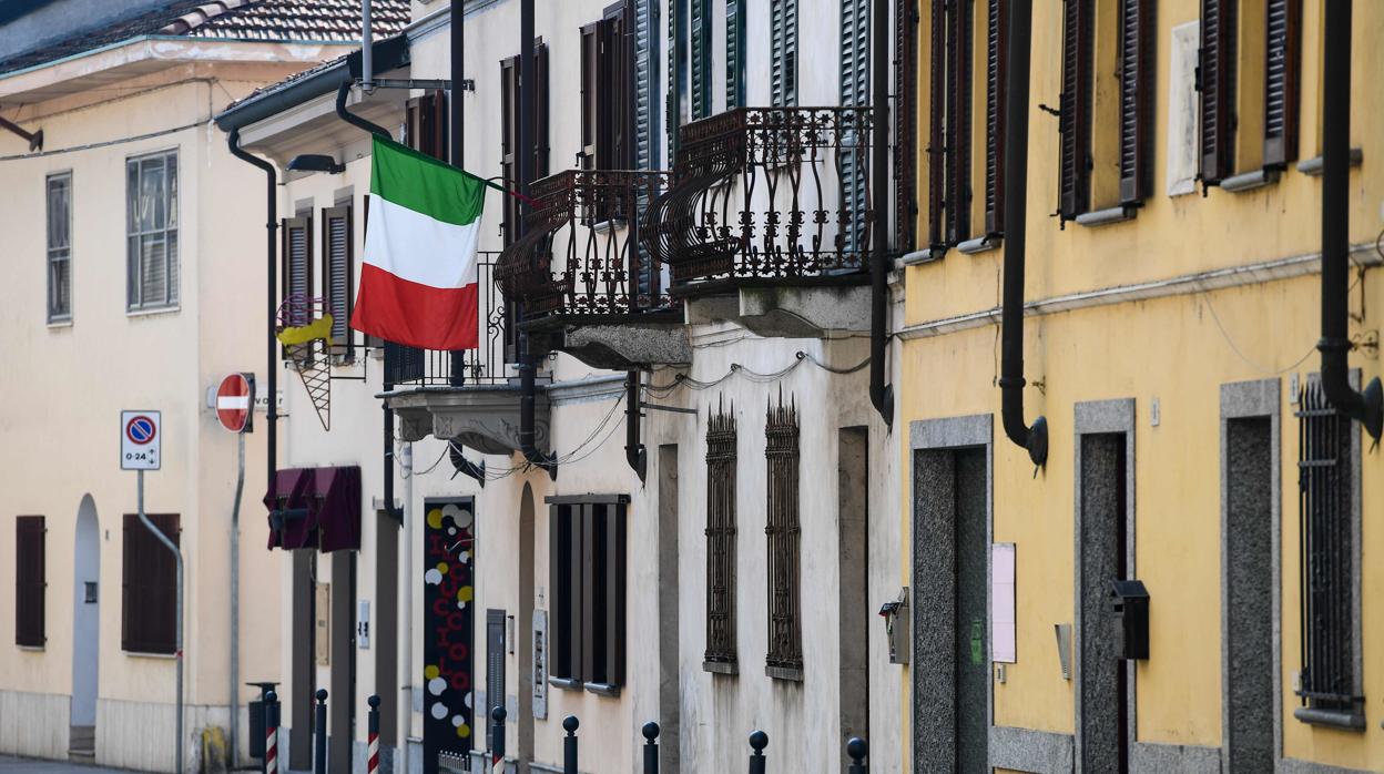 Calle desierta y una bandera italiana en un balcón de la ciudad Robbio, al norte del país