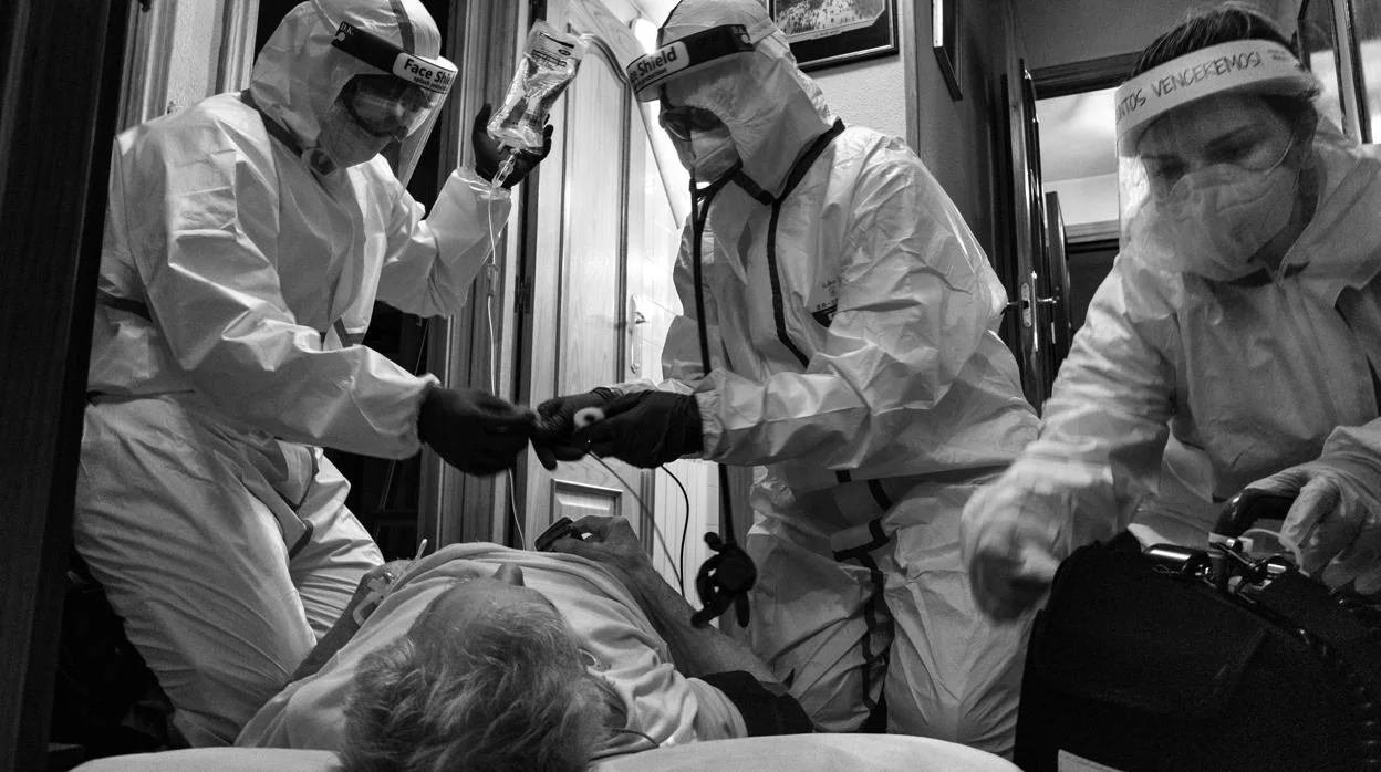Un equipo de la unidad de emergencias medicas de Madrid (SUMMA) atiende a un paciente sospechoso de ser positivo de COVID 19 en el interior de su casa