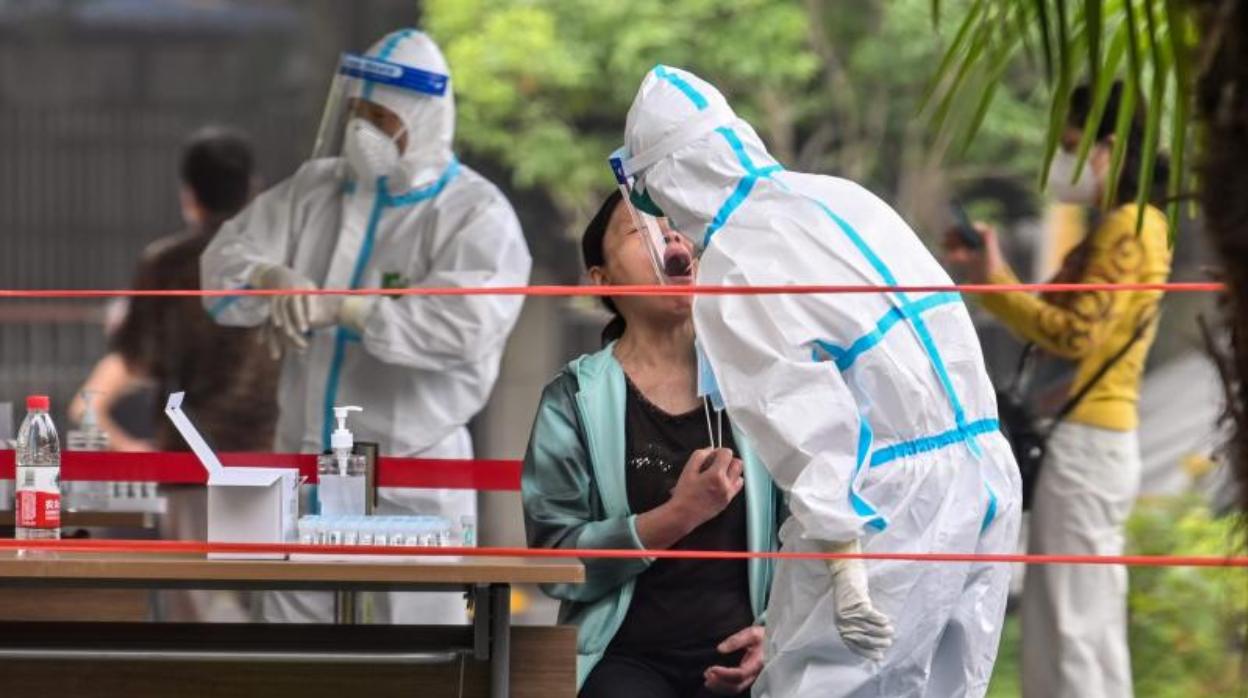 Un trabajador toma una muestra para ser analizada en un vecindario de Wuhan