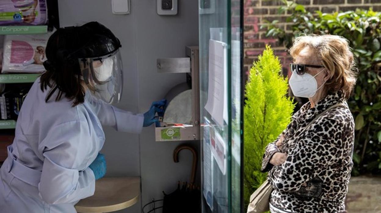 Una persona recoge su mascarilla en una farmacia de Madrid