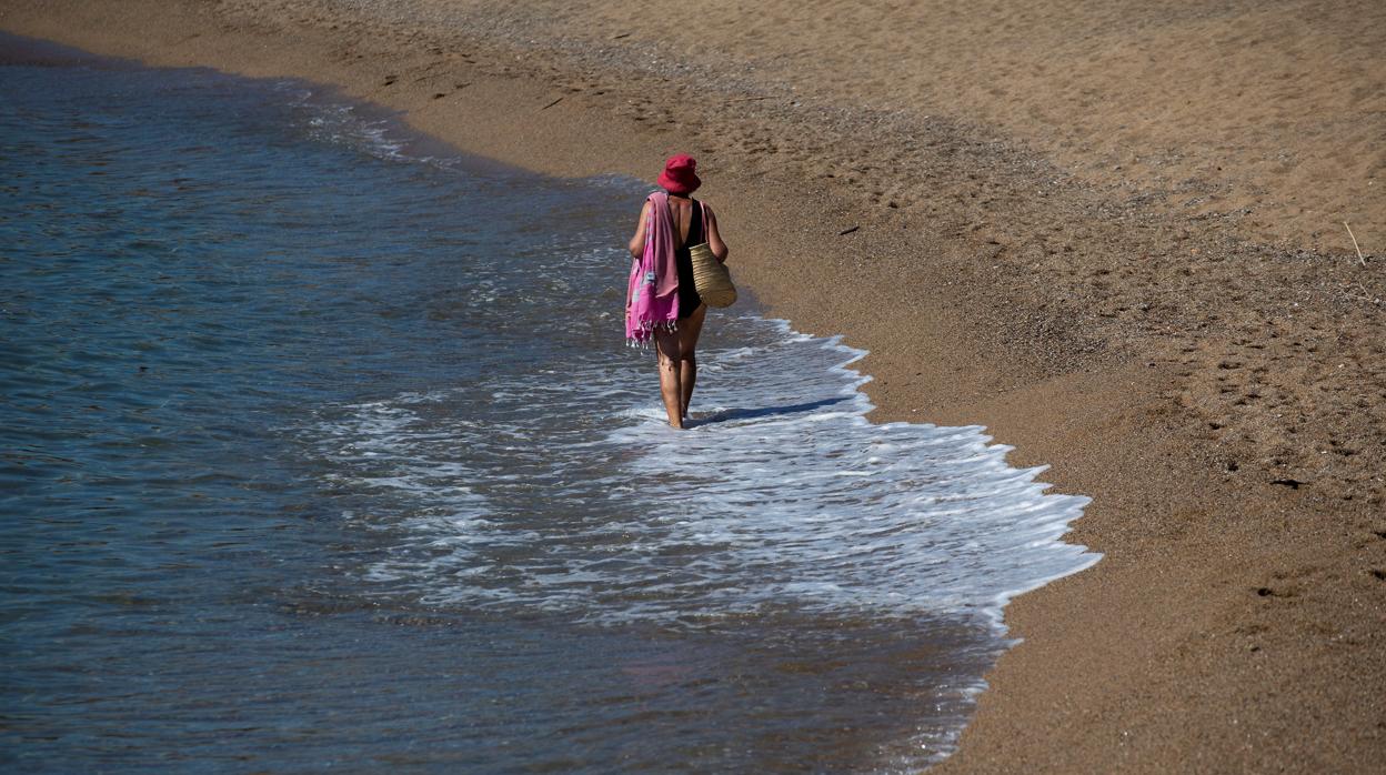 Una mujer pasea por la orilla de una playa