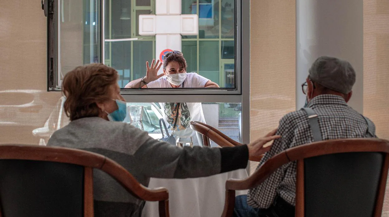Una persona conversa con sus padres a través de una ventana habilitada en la residencia de mayores Ballesol Patacona, en Valencia
