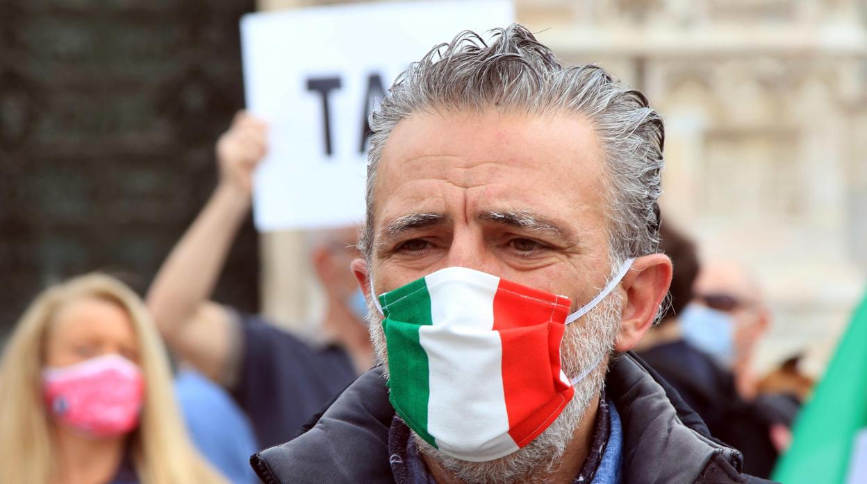 Un hombre lleva una mascarilla con la bandera italiana en una manifestación de Milán