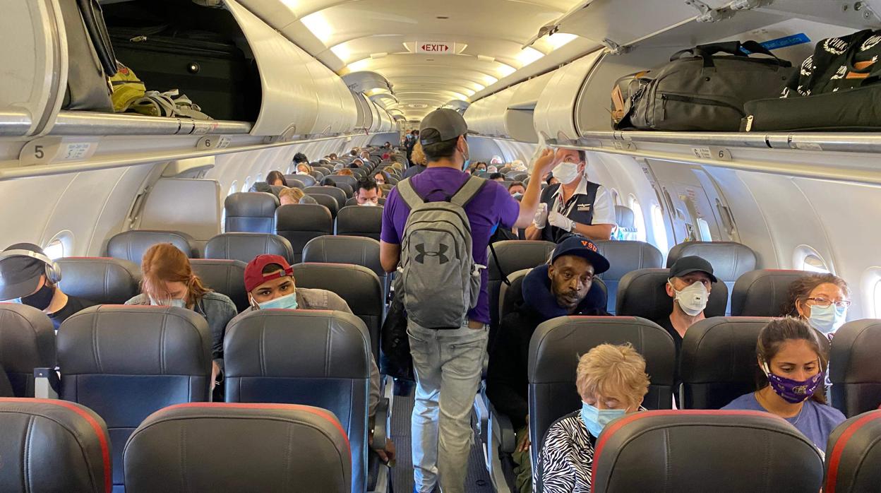 Pasajeros de un avión protegiéndose boca y nariz con la mascarilla