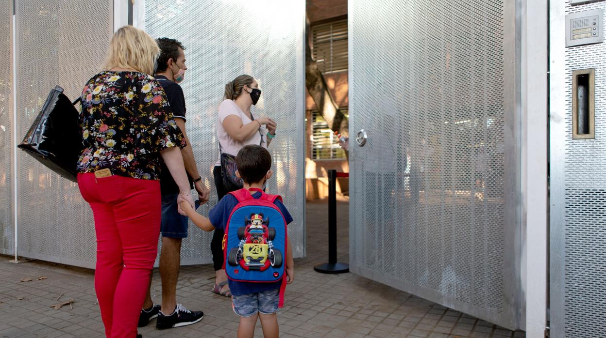 Un niño espera junto a sus padres para entrar al colegio