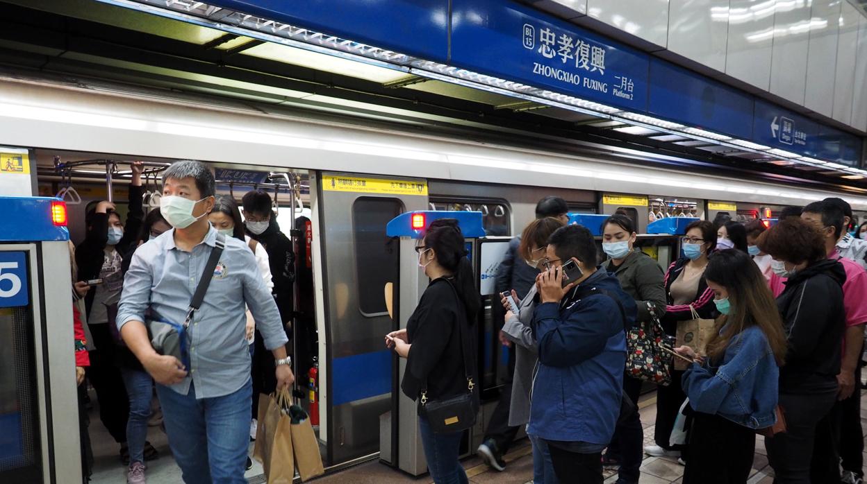 Varias personas esperan con la mascarilla puesta para entrar en un tren de Taipei, Taiwán