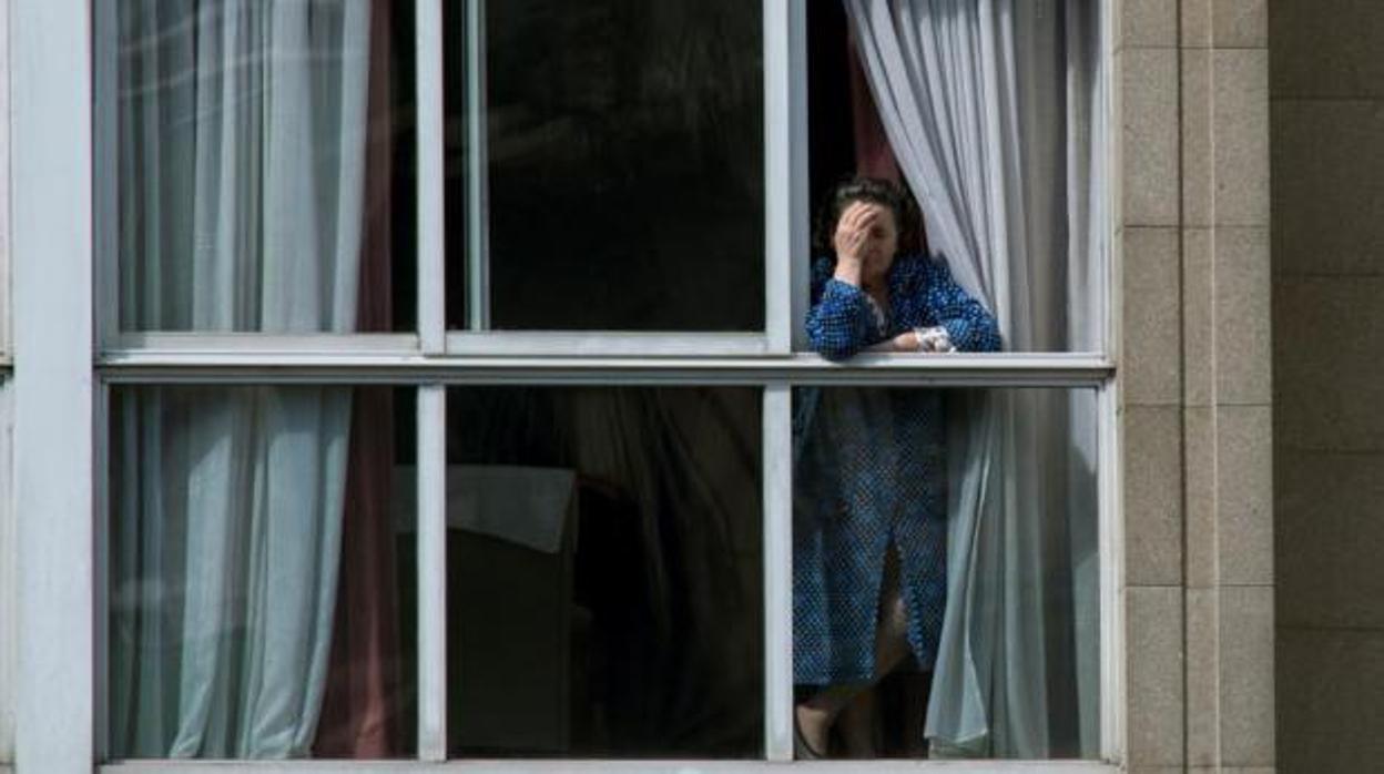 Una mujer se asoma por la ventana desesperada