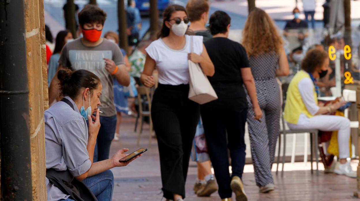 Una mujer, a mediados de agosto, fumando en una calle de Oviedo