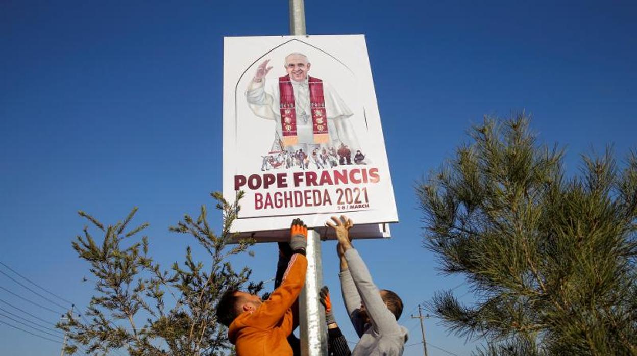 Un grupo de voluntarios cuelga carteles de bienvenida al Papa Francisco