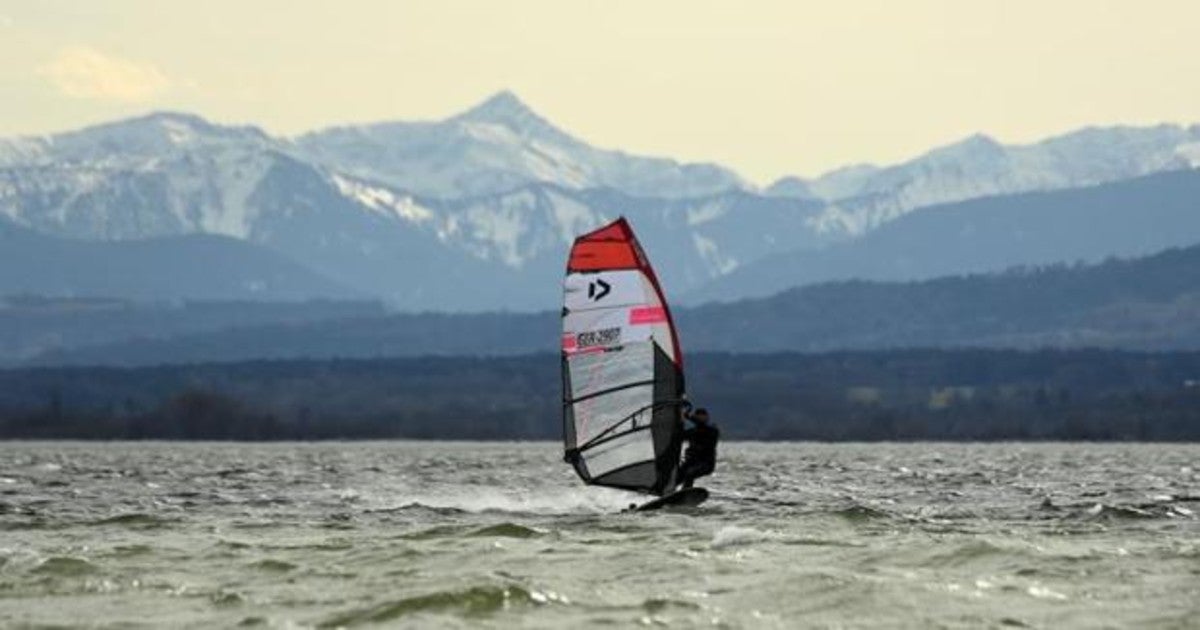 Un surfista frente a las montañas de los Alpes, en el lago Ammersee cerca de Herrsching, en el sur de Alemania, durante una tormenta el 13 de marzo de 2021