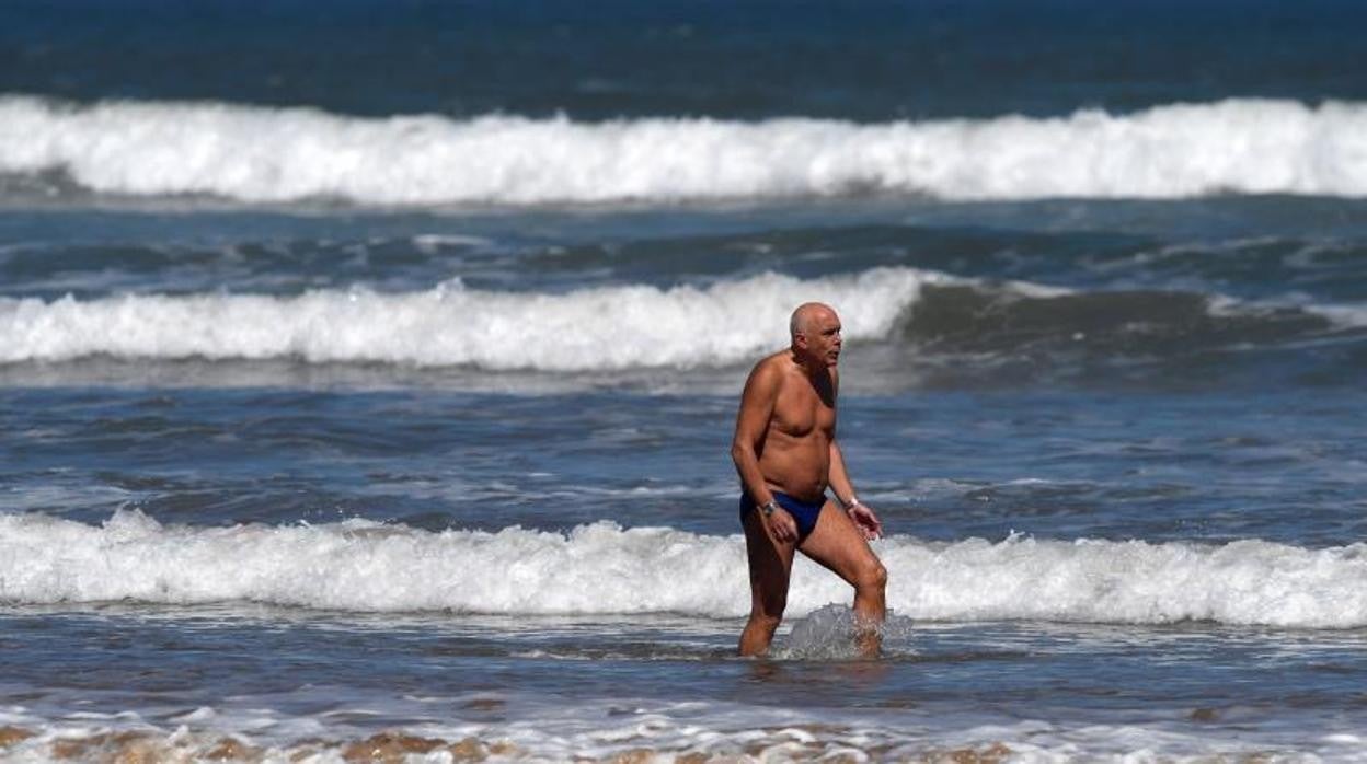 Un hombre disfruta del agua en la playa de San Lorenzo de Gijón este domingo