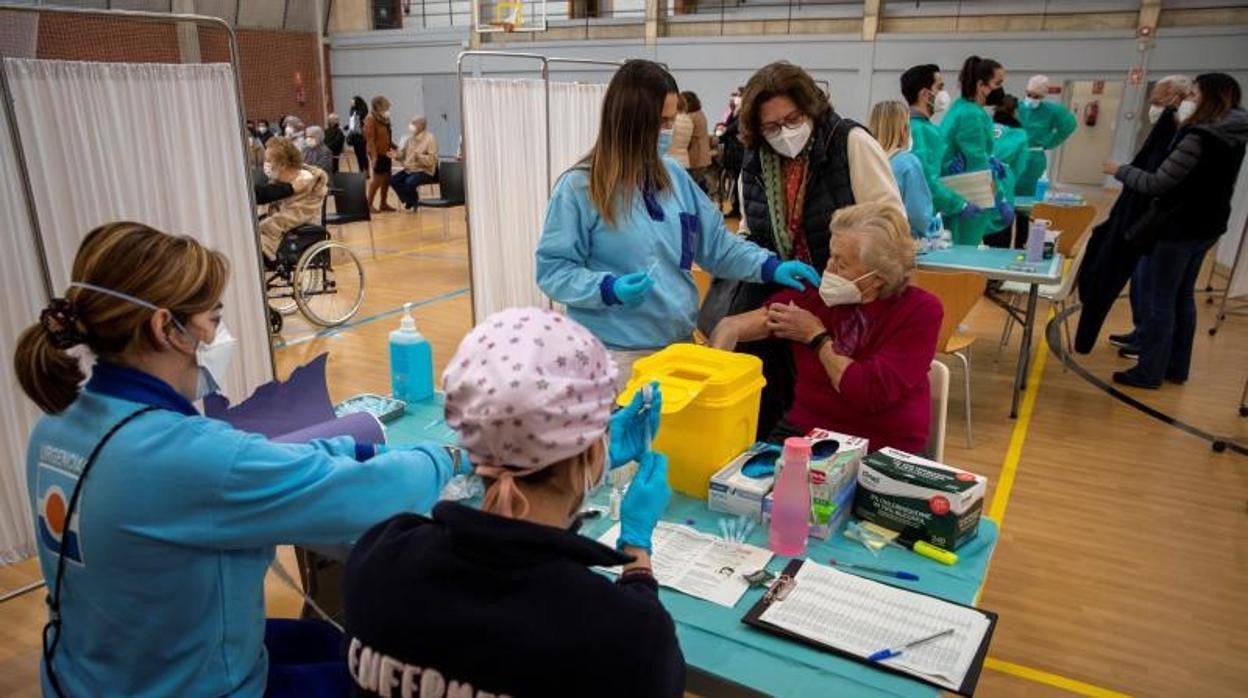 Sanitarias vacunan a una persona mayor de 80 años en un pabellón deportivo de la Universidad de Sevilla