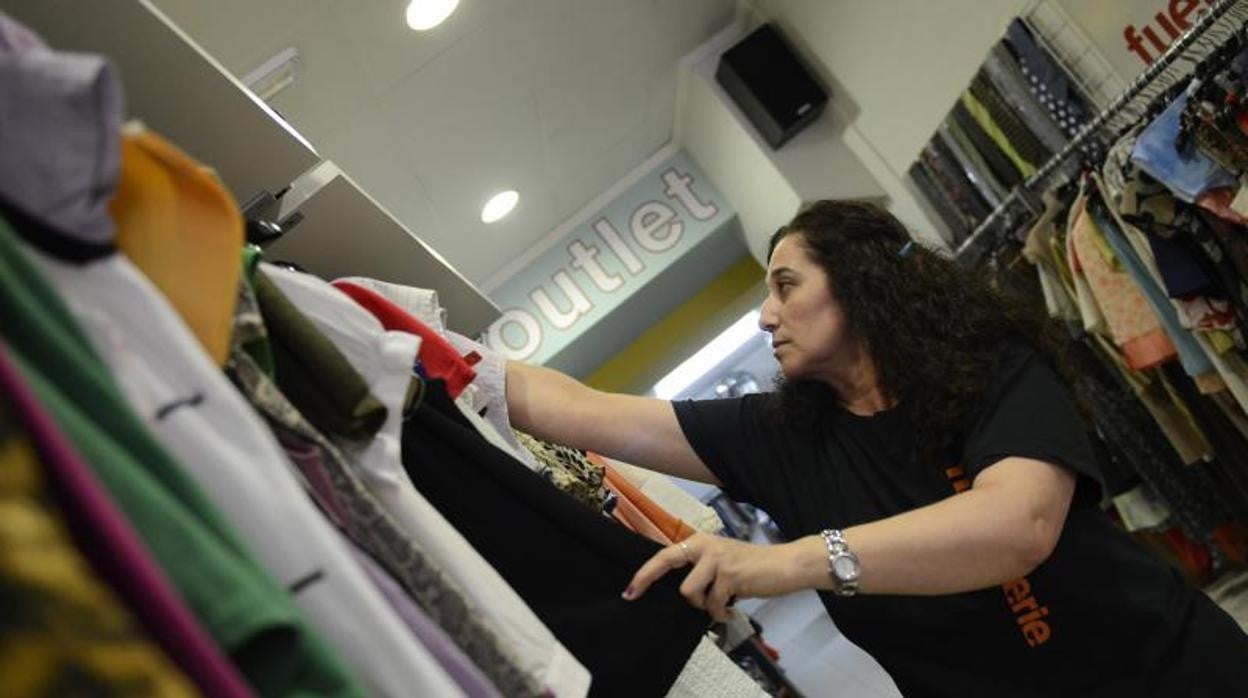 Una mujer trabaja en una tienda de ropa reciclada de Cáritas en Albacete