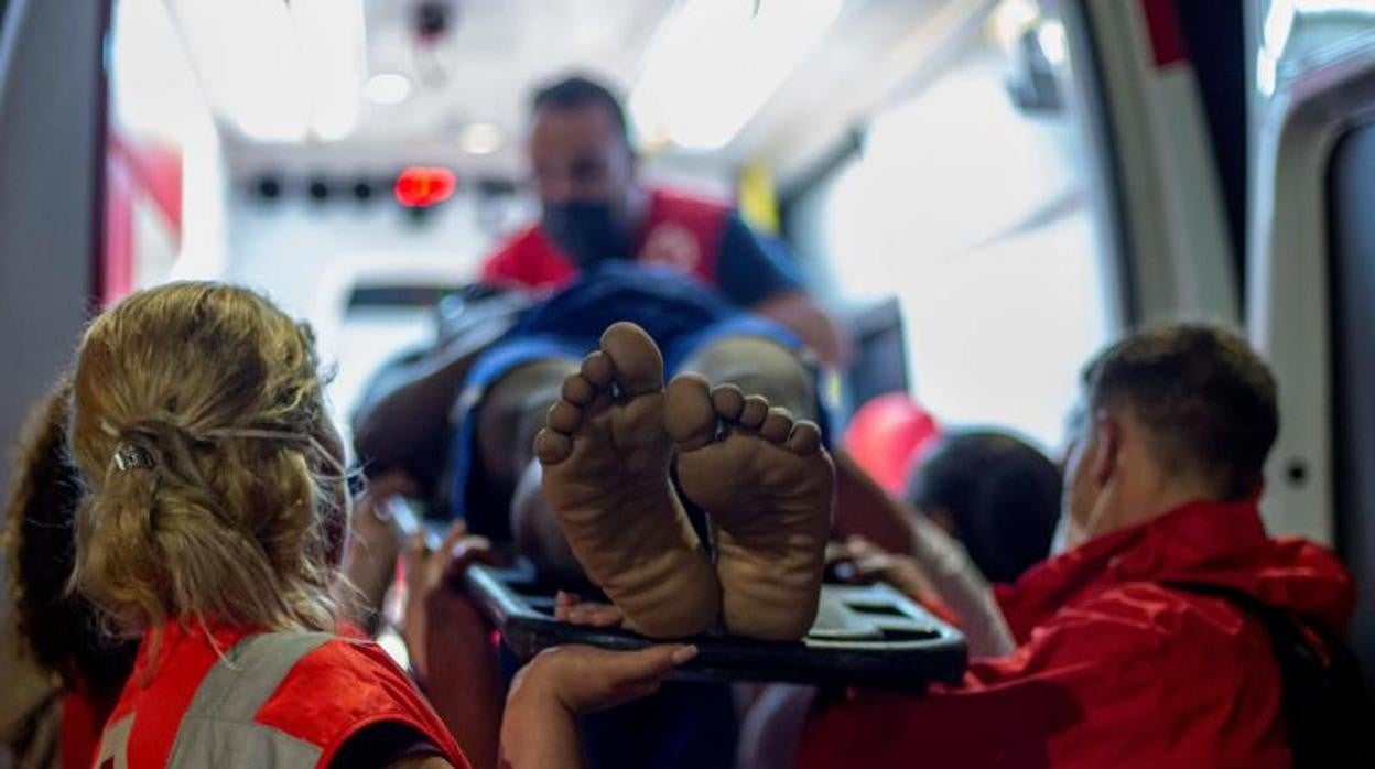 Efectivos de Cruz Roja trasladan en ambulancia a un inmigrante con signos de hipotermia tras intentar cruzar a España por el agua en la playa de El Tarajal