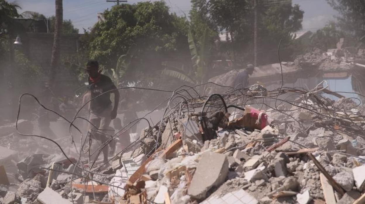 Un grupo de personas remueve escombros en una calle de Los Cayos