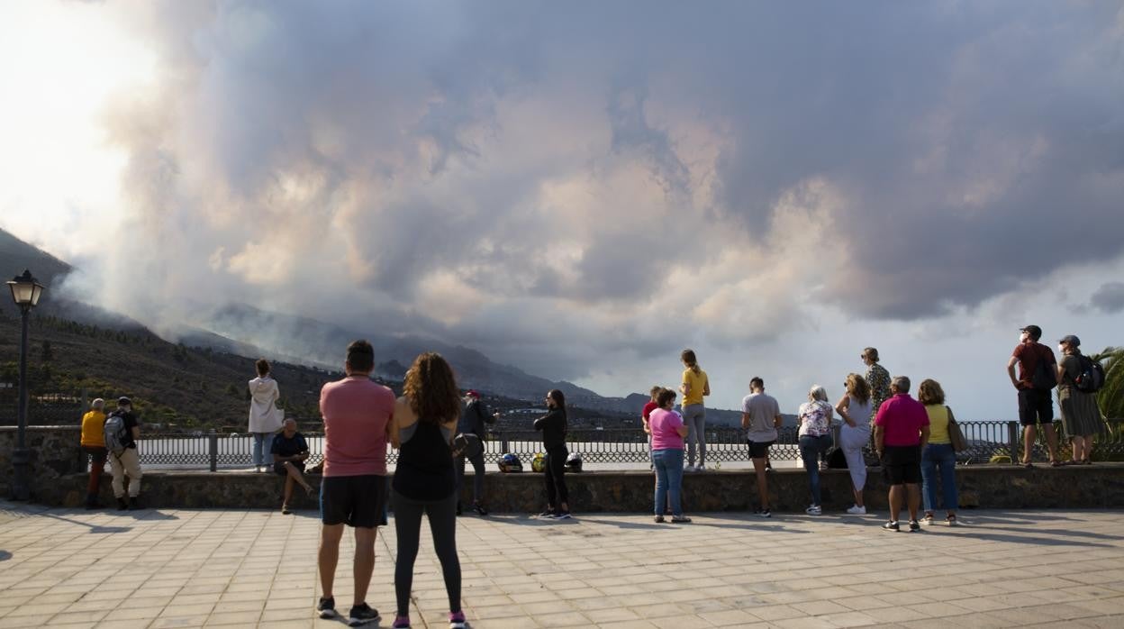 Unas personas miran la nube del volcán de La Palma. Esta tiene presencia de dióxido de azufre