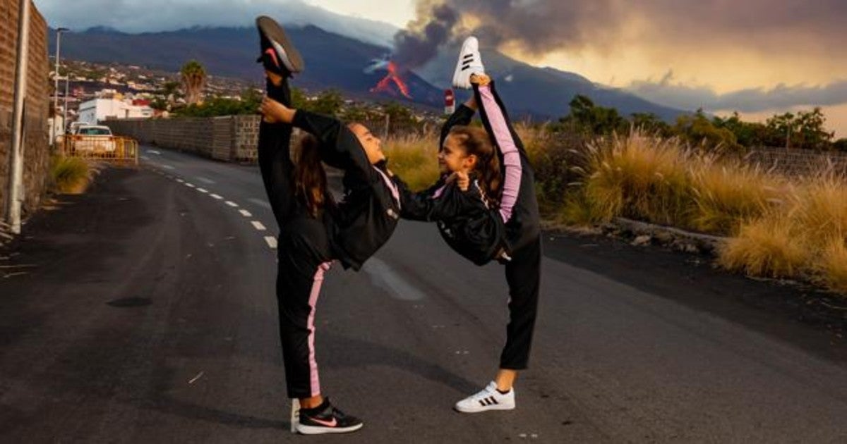Aura y Alejandra improvisan un movimiento de gimnasia con el volcán al fondo, arrojando fuego