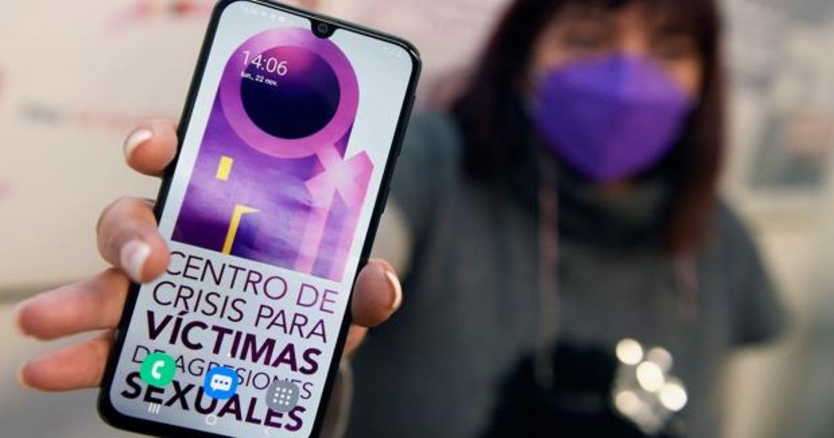 Una mujer sostiene un teléfono que muestra un centro de crisis para atender a las víctimas de violencia sexual.