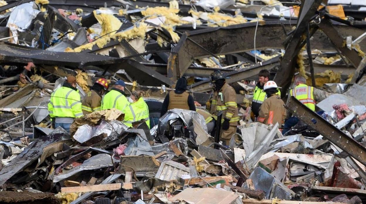 Trabajadores de emergencia registran lo que queda de la fábrica de velas de productos de consumo Mayfield después de que fuera destruida por un tornado