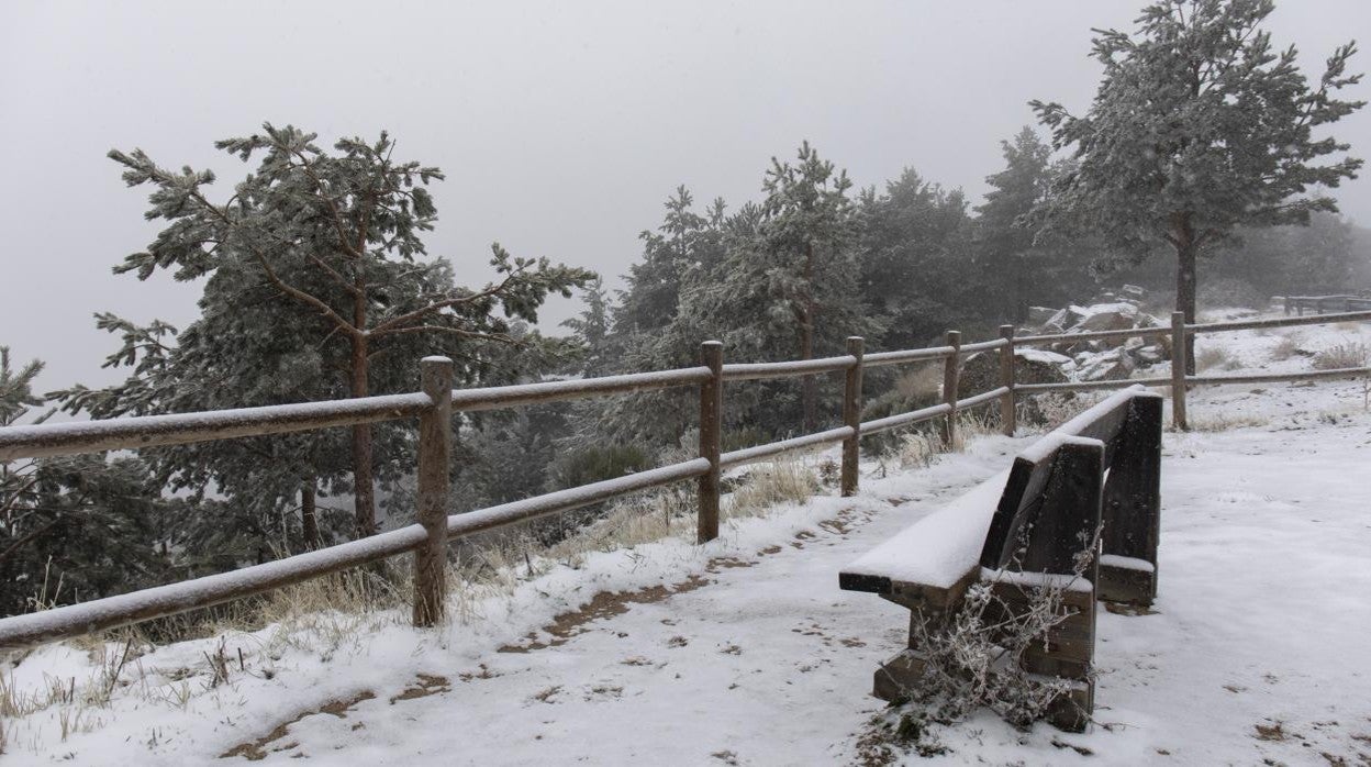 Un banco en el Puerto de Navacerrada (Madrid) rodeado de nieve, en la sierra de Guadarrama, a 4 de noviembre de 2021