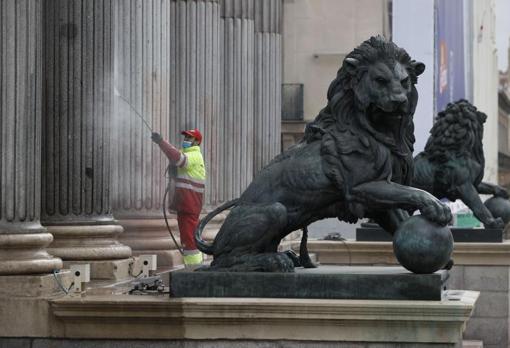 Un operario limpia las manchas de pintura roja de la fachada del Congreso de los Diputados