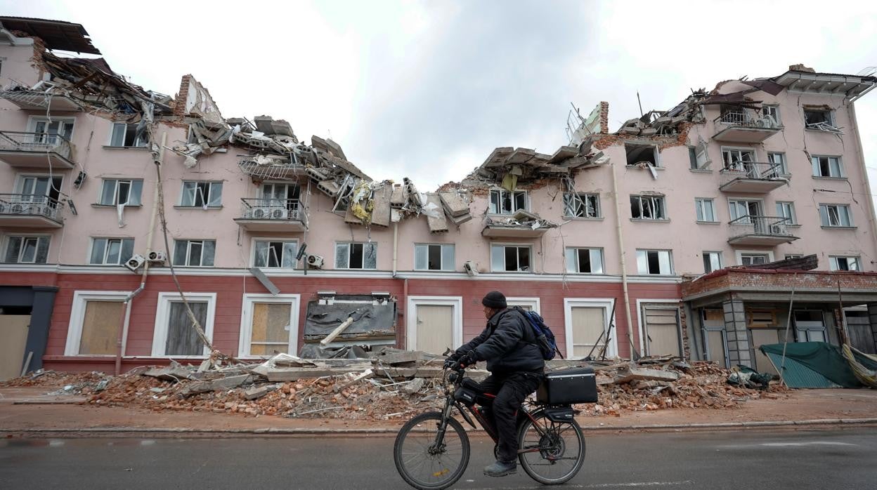 Un hombre en bicicleta pasea junto al hotel Ucrania, destruido en Chernihiv