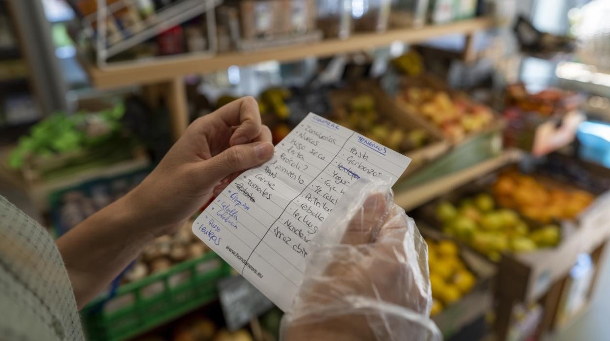 Una mujer lee la lista de alimentos que tiene que comprar