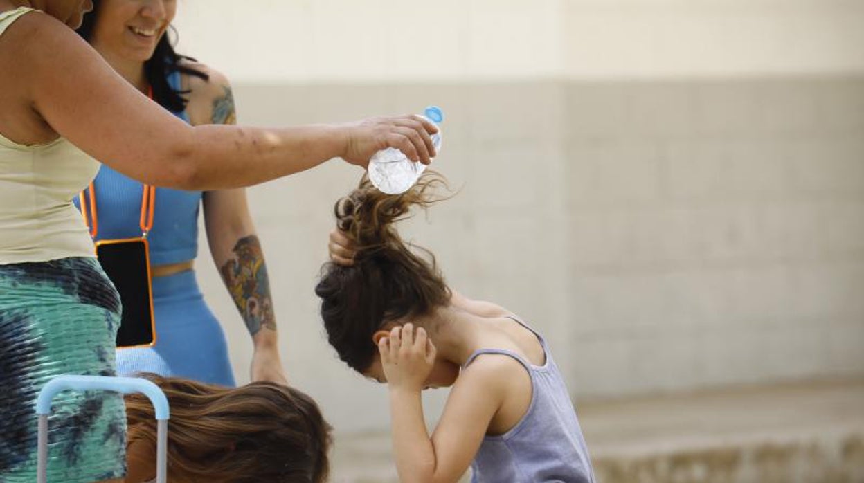 Varias madres del colegio Mediterráneo de Córdoba refrescan a sus hijos con botellas de agua tras sacarlos del centro