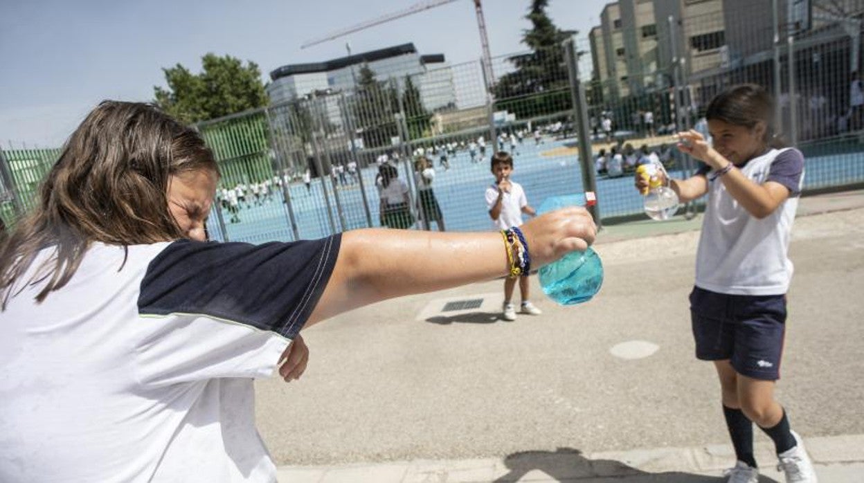 Unos alumnos del colegio Santa Joaquina de Vedruna juegan, a la par que se refrescan, con sus botellas de agua