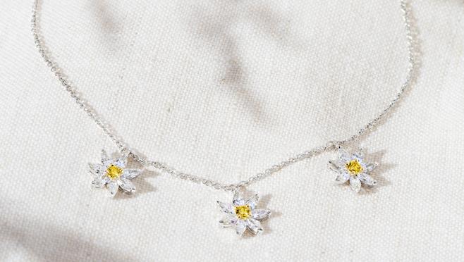 Colgante con charms en forma de margarita, en oro blanco de 18 quilates con diamantes Fancy talla brillante, diamantes blancos talla marquise (3,890 €)