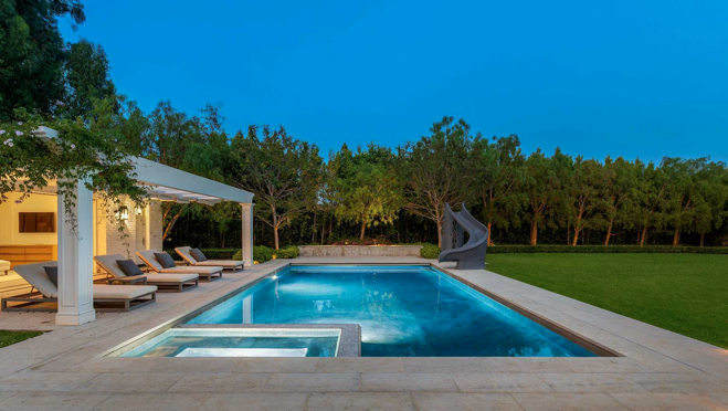 La zona exterior incluye piscina con spa, comedor y cocina, así como una gran zona de césped