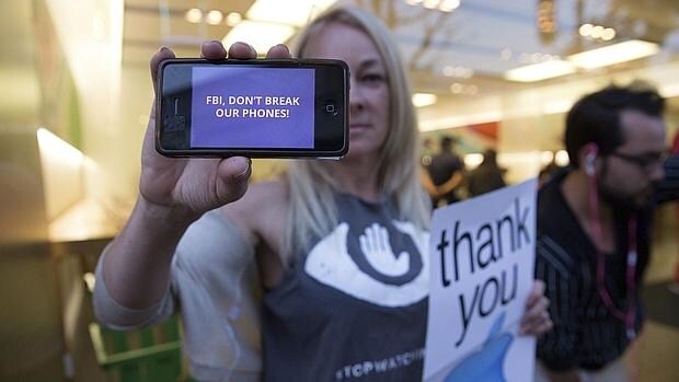 Una mujer sostiene su iPhone en el se lee «FBI, no rompas nuestros teléfonos»