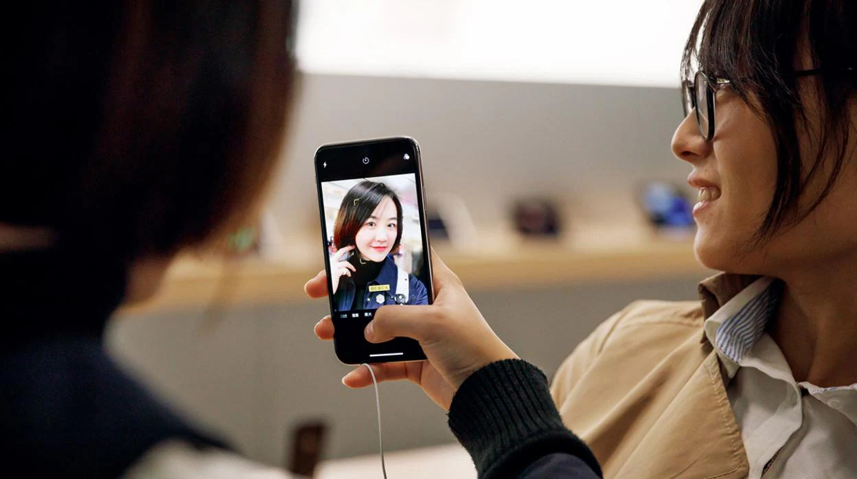 Una joven se hace un «selfie» en una App Store de Shanghai con un iPhone X