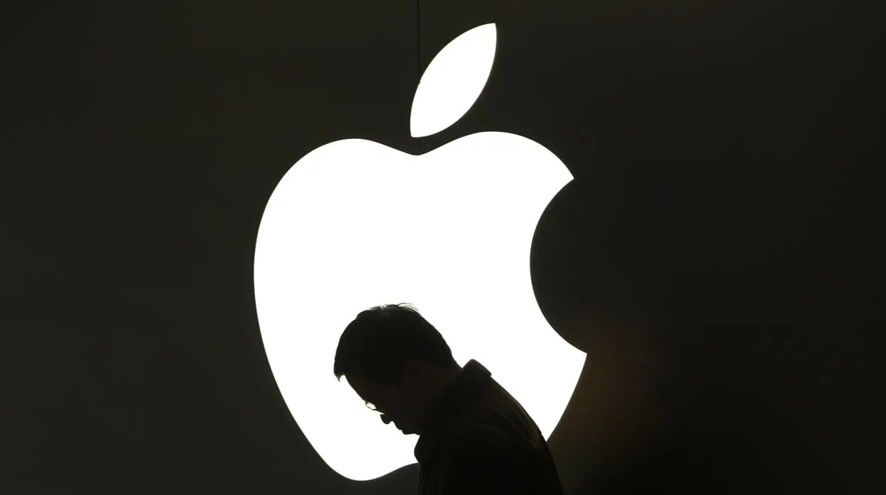Una persona posa ante un logo de la firma de la manzana