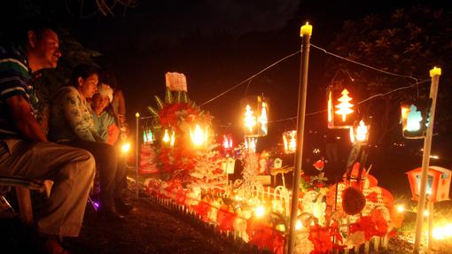 Una familia enciende velas en un cementerio durante la "Noche de las velitas", en Cali (Colombia)