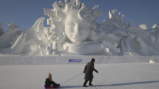 Un hombre y su hija juegan junto a una escultura de nieve de 31 metros de alto en la trigésimo tercera edición del Festival Internacional de Hielo y Nieve de Harbin (China)