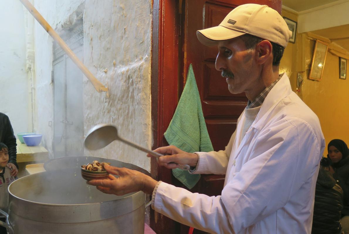 En la imagen, el veterano vendedor de caracoles Ahmed en su local, ubicado en la medina de Rabat, sirve tazones calientes a sus clientes