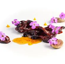 Plato de almeja Geoduck con manzanilla silvestre de piña fermentada y flores de amapola de California