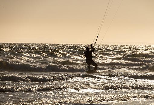 Practicando kitesurf mientras atardece en una playa de Huelva