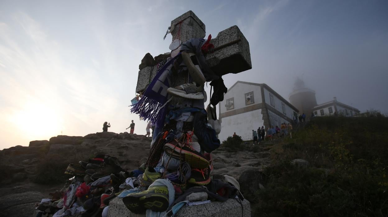 La Cruz del fin del Camino de Finisterre, con el faro al fondo entre la niebla